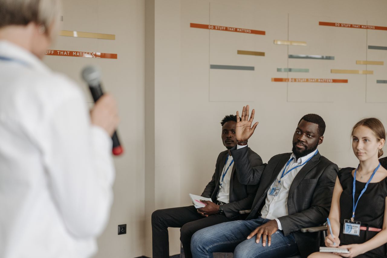Engaged participants in a business conference, raising questions to the speaker.